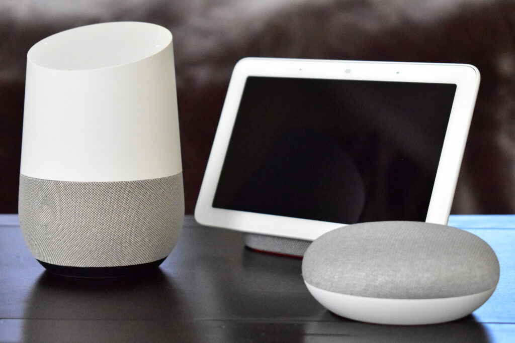 A Google Home Hub touchscreen and a Google Home Mini speaker sitting on a wooden table