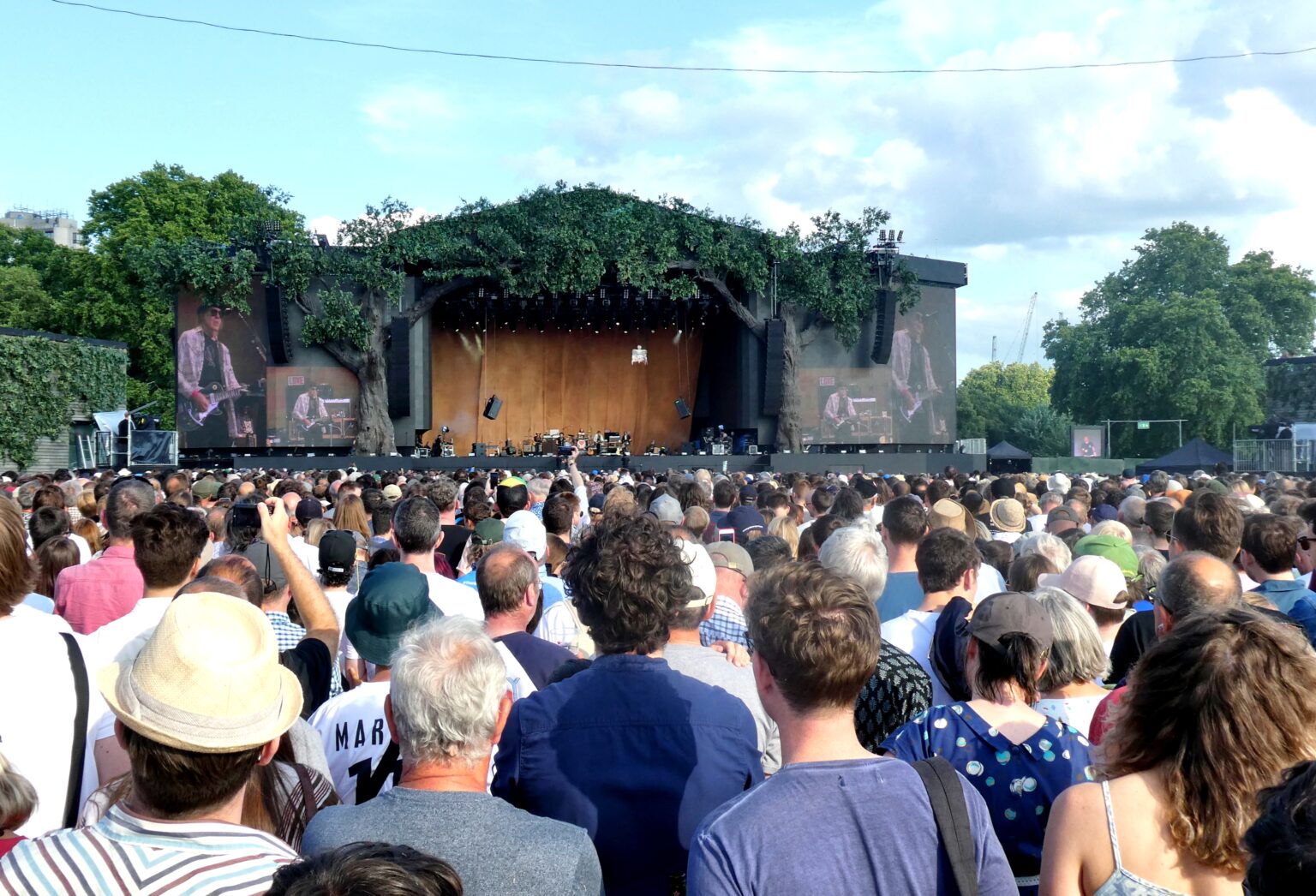 A wide view of a large concert crowd filling an open-air venue in front of the stage